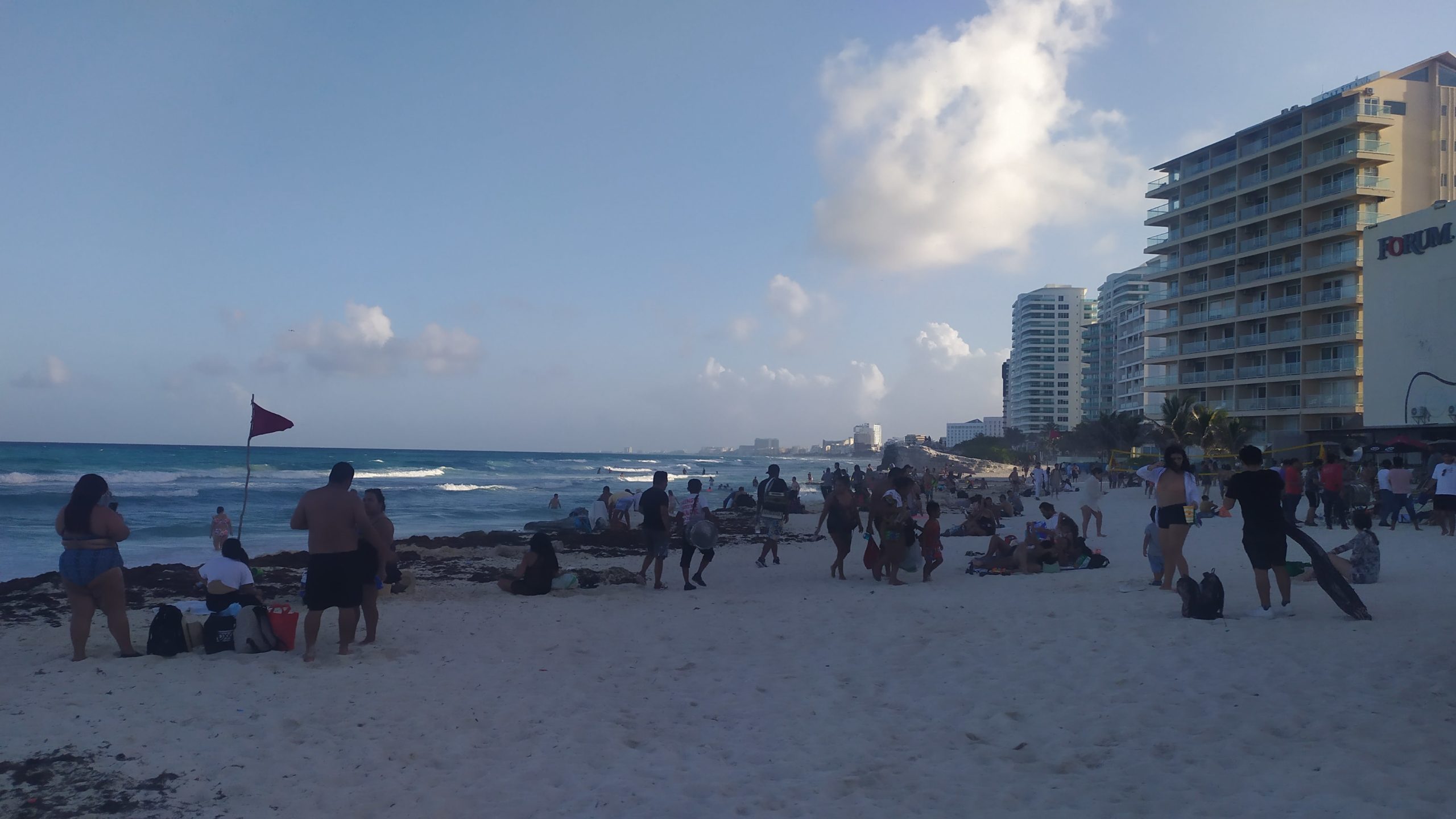 une plage bondée de Cancun avec de nombreux touristes et une rangée d'hôtels à droite