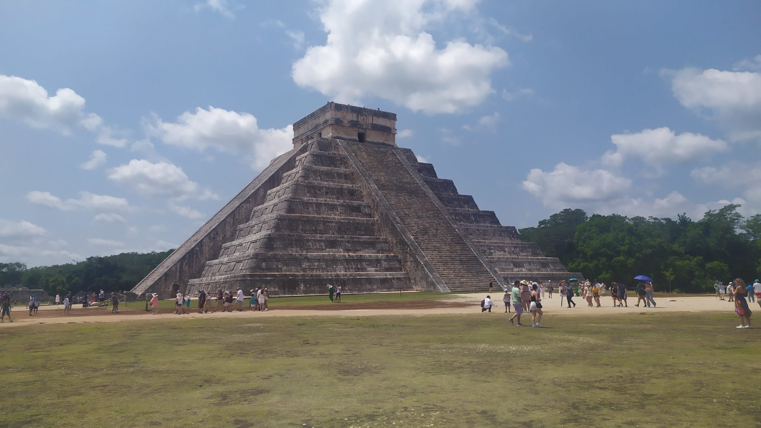 Une des nombreuses pyramides de chichen itza se dresse devant moi. des touristes se tiennent aux abords, téléphones en main